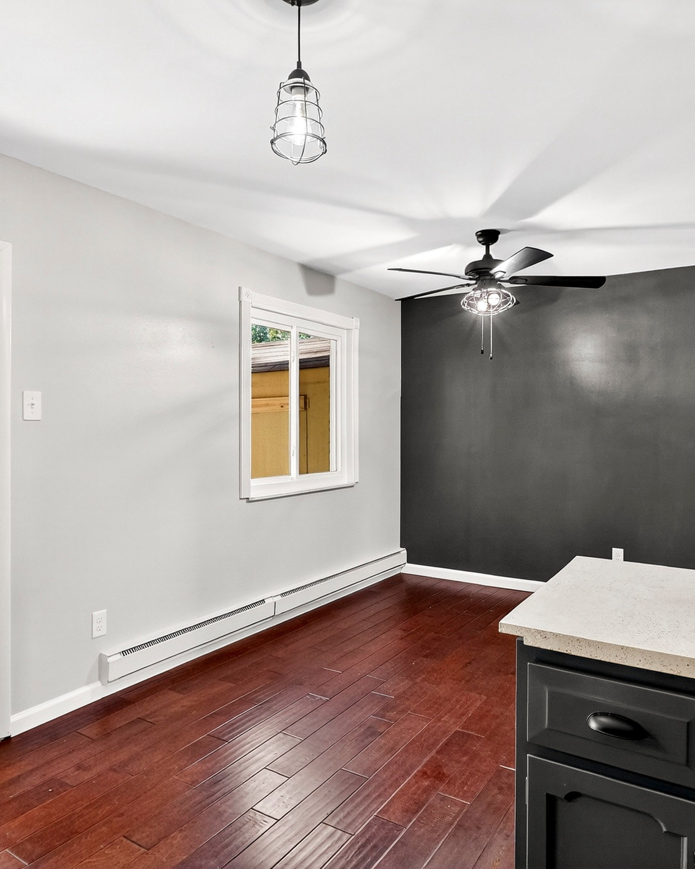 Modern interior of a room with wooden flooring, white walls, and black cabinets.