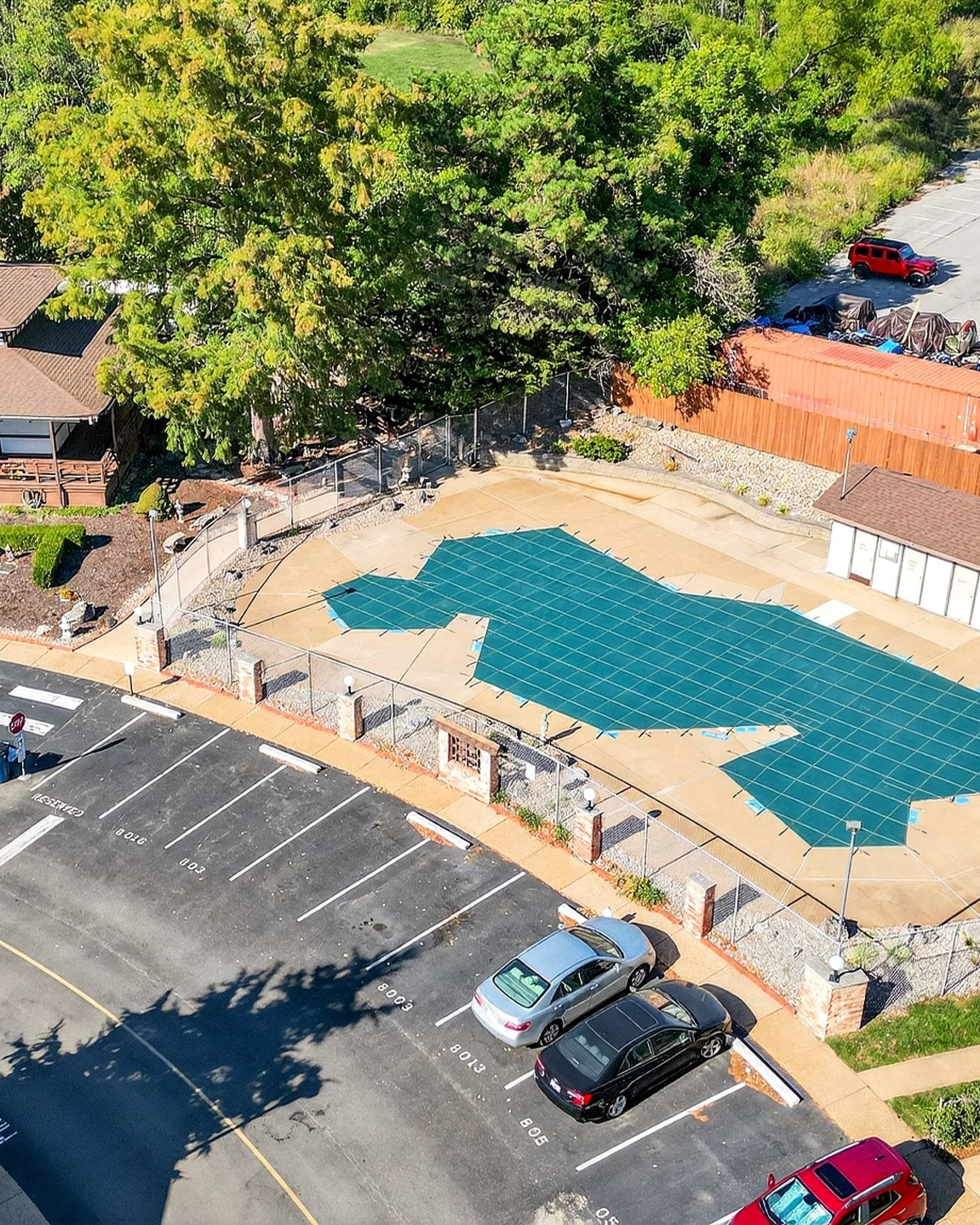 Aerial view of a pool area with surrounding parking lot and trees