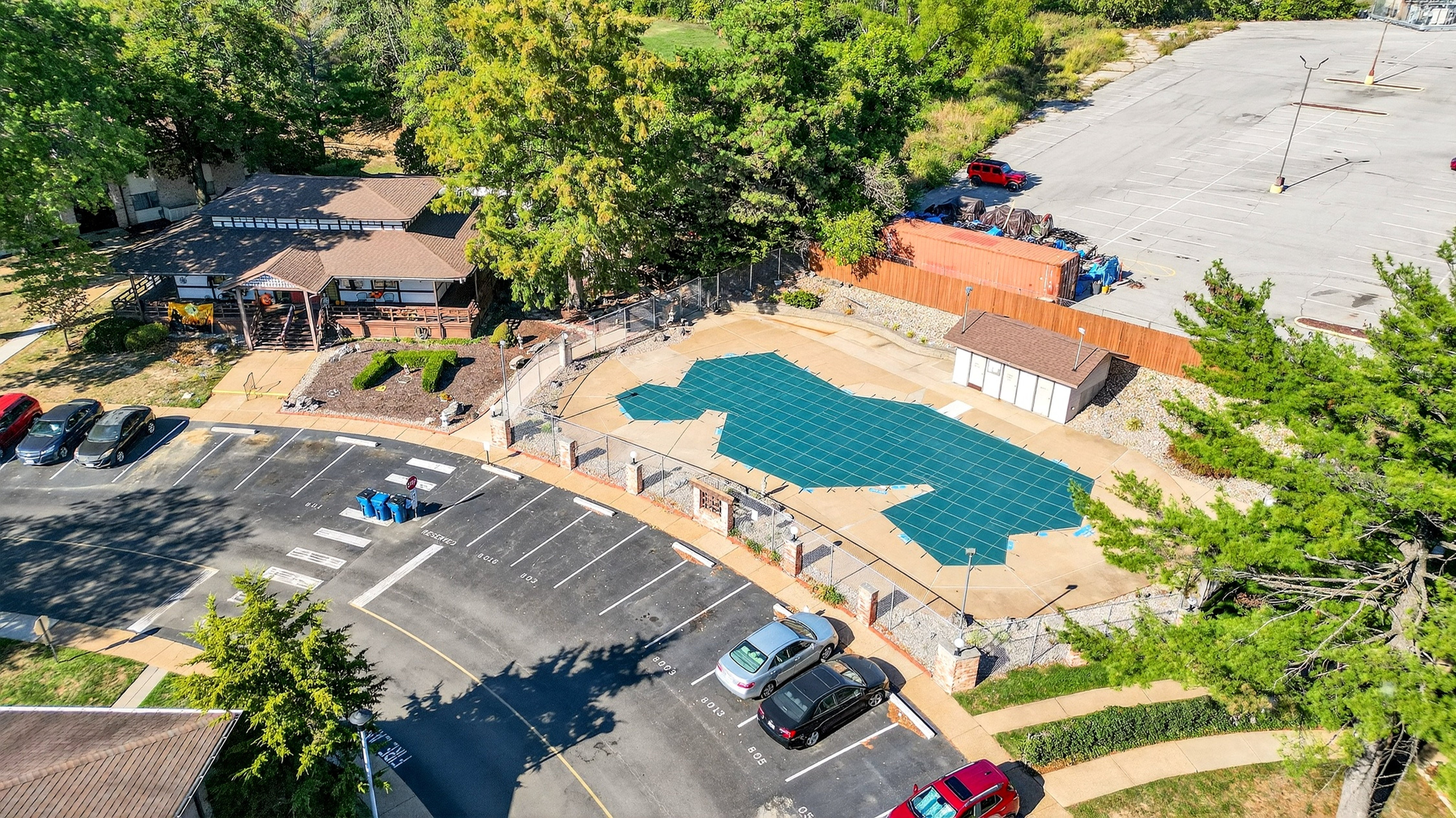 Aerial view of a pool area with surrounding parking lot and trees