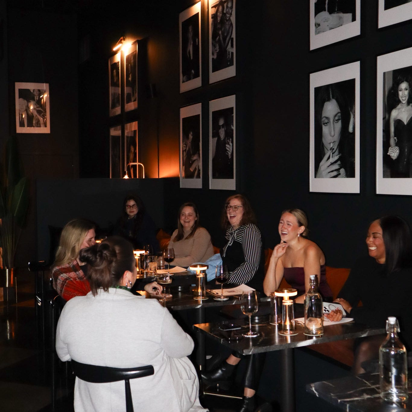 People sitting at a table in a dimly lit room with framed pictures on the wall.