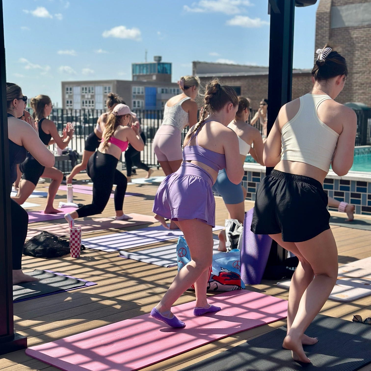Group of people participating in a rooftop yoga class on a sunny day.