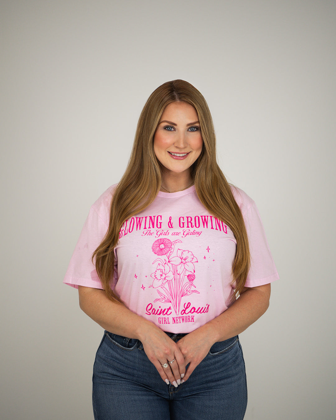 Woman wearing a pink t-shirt with text and graphics on a plain background