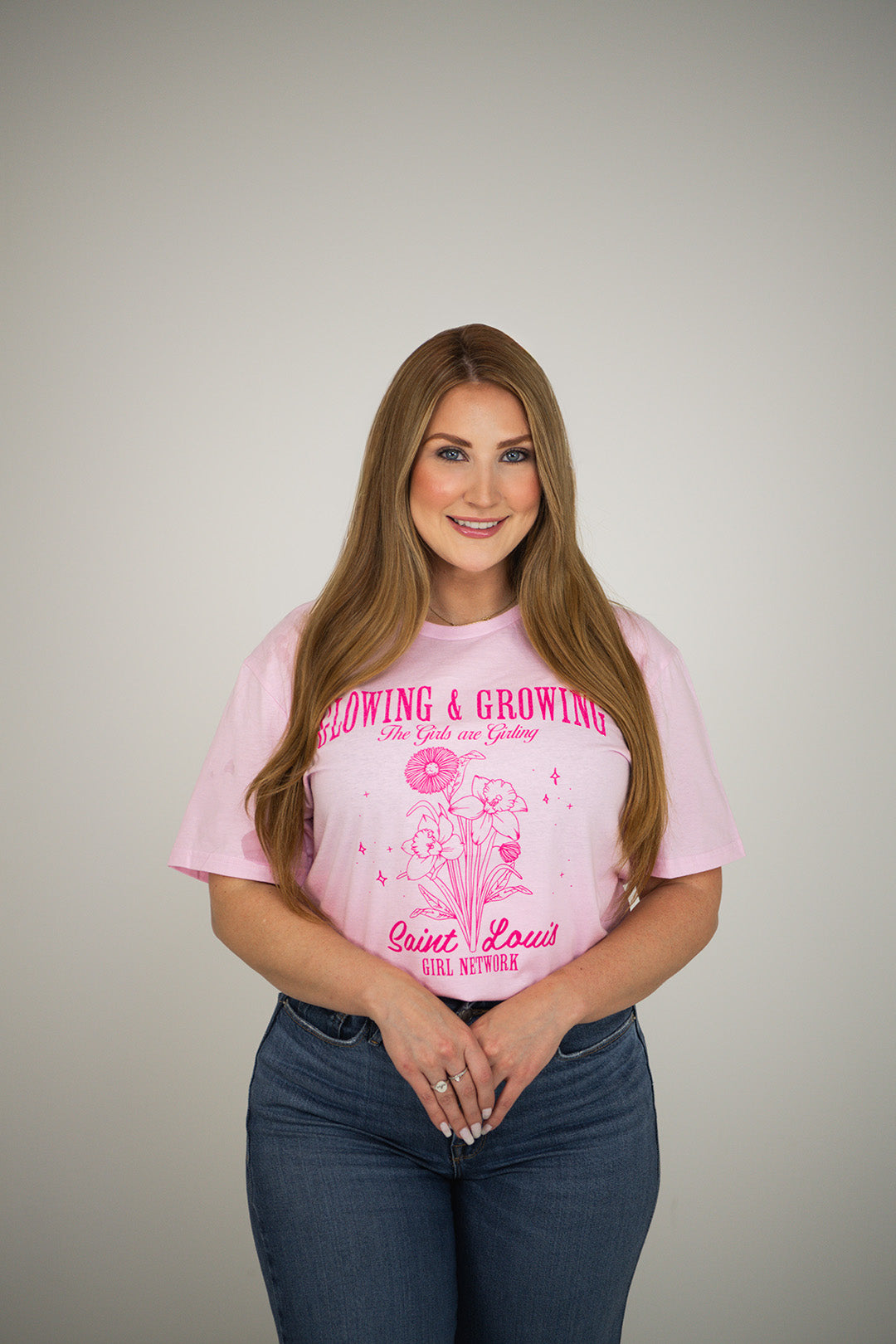 Woman wearing a pink t-shirt with text and graphics on a plain background