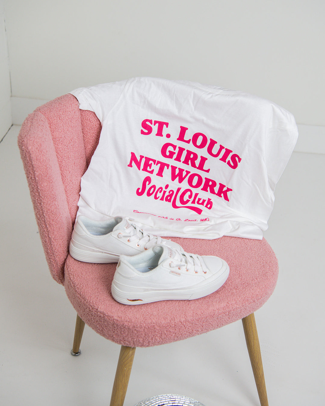 White t-shirt with pink text on a pink chair against a white background