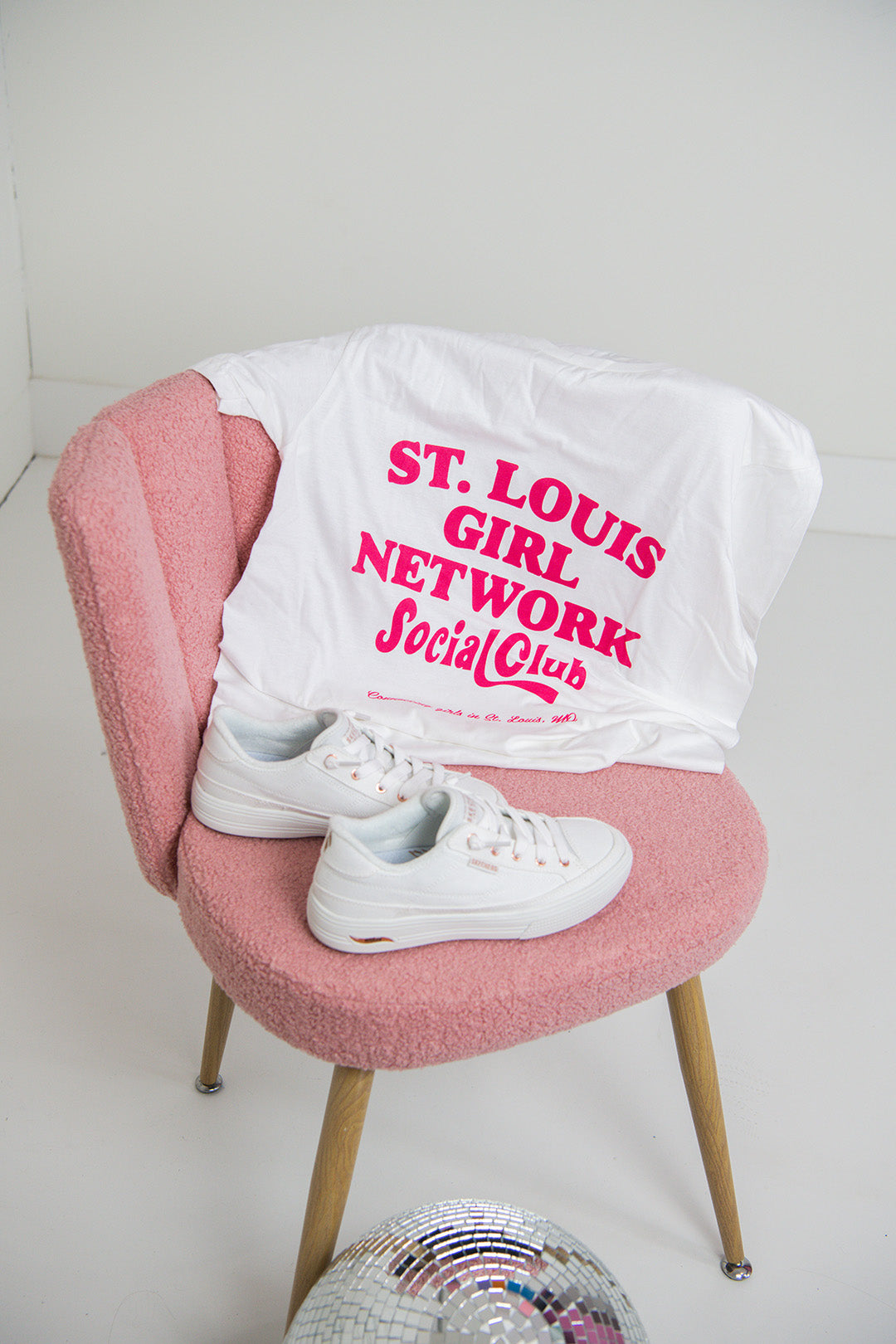 White t-shirt with pink text on a pink chair against a white background