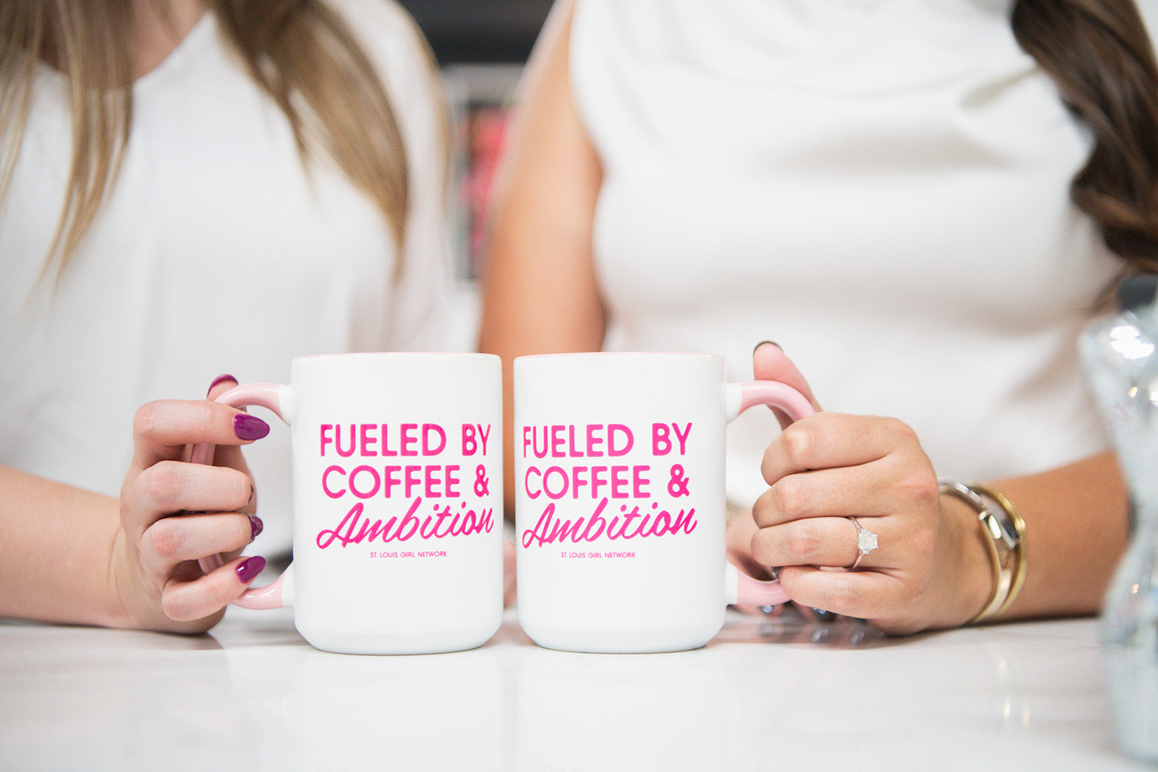 Two people holding mugs with 'Fueled by Coffee & Ambition' text.