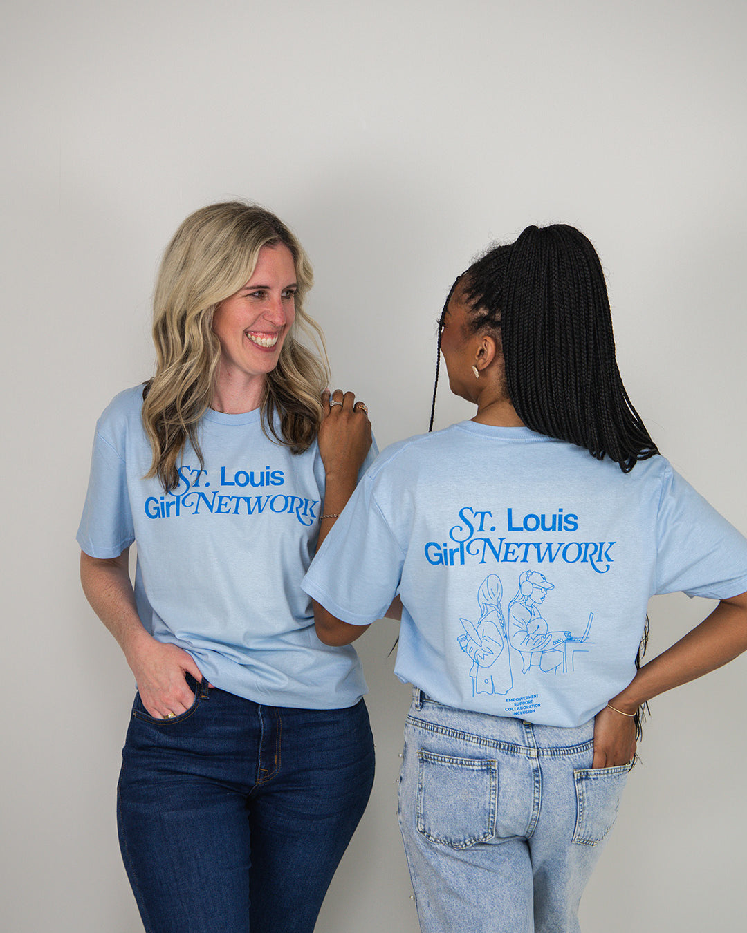Two people wearing light blue t-shirts with 'St. Louis Girl Network' text, one facing the camera and the other showing the back.