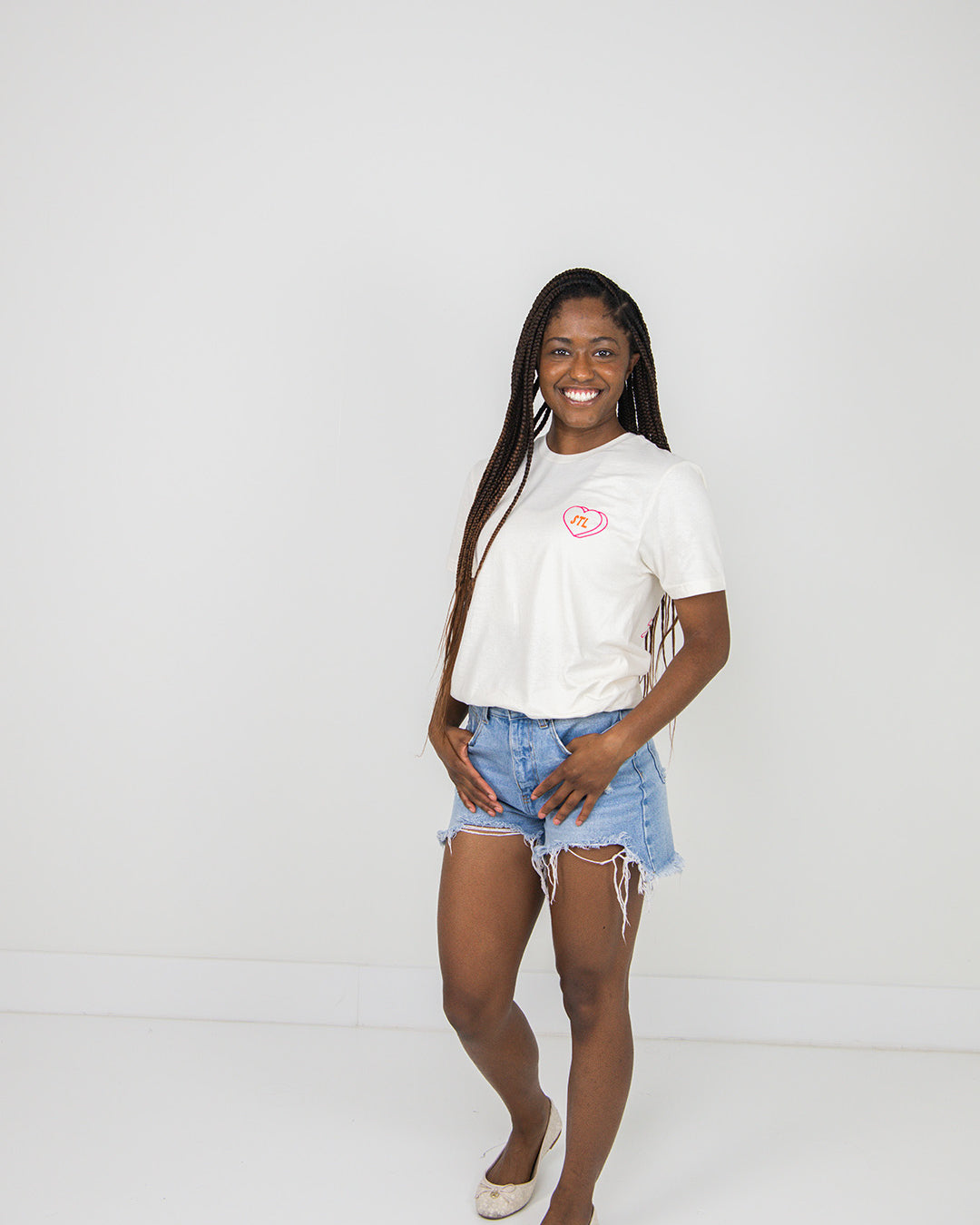 Woman wearing a beige t-shirt and denim shorts on a plain background