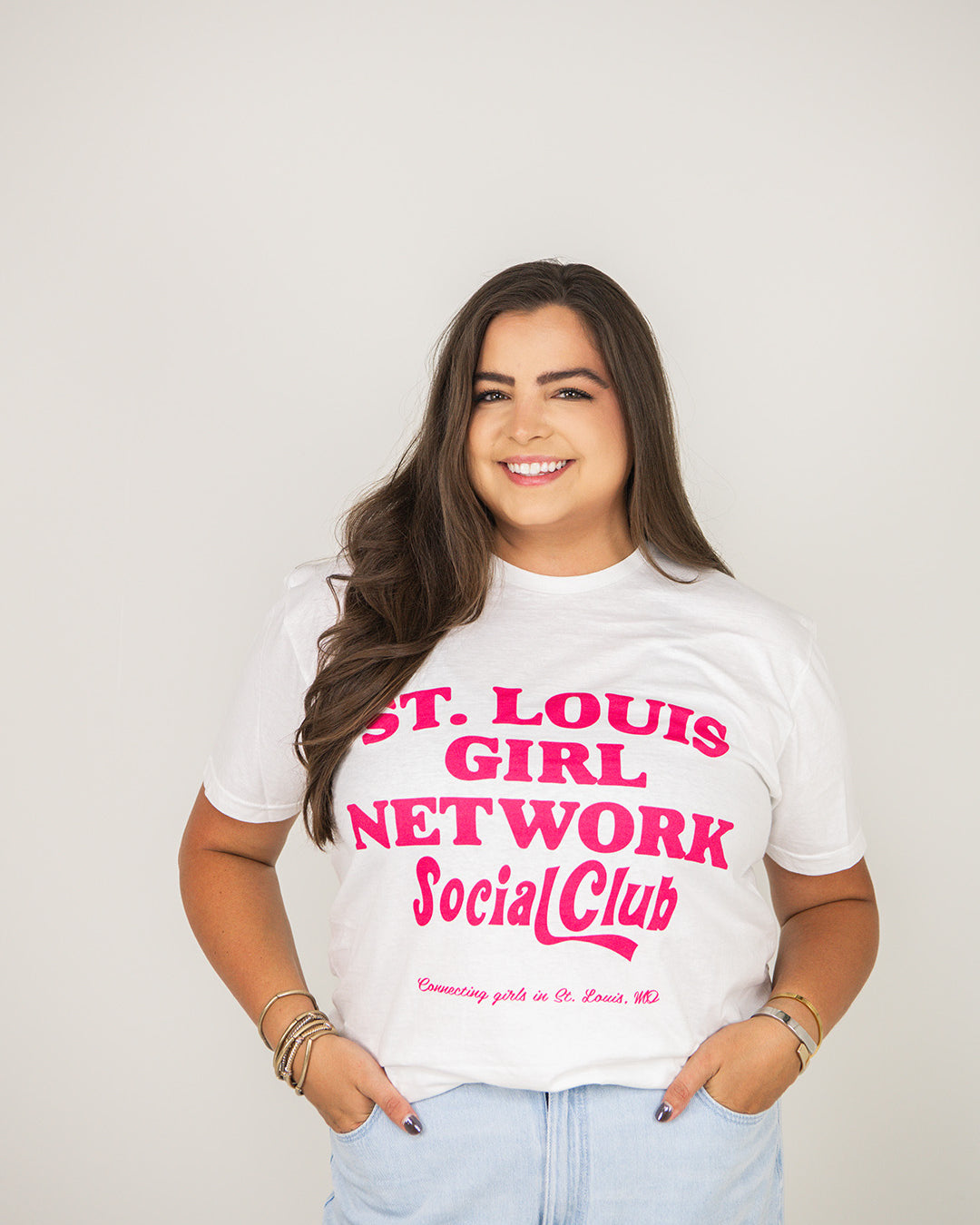 Woman wearing a white t-shirt with pink text against a plain background