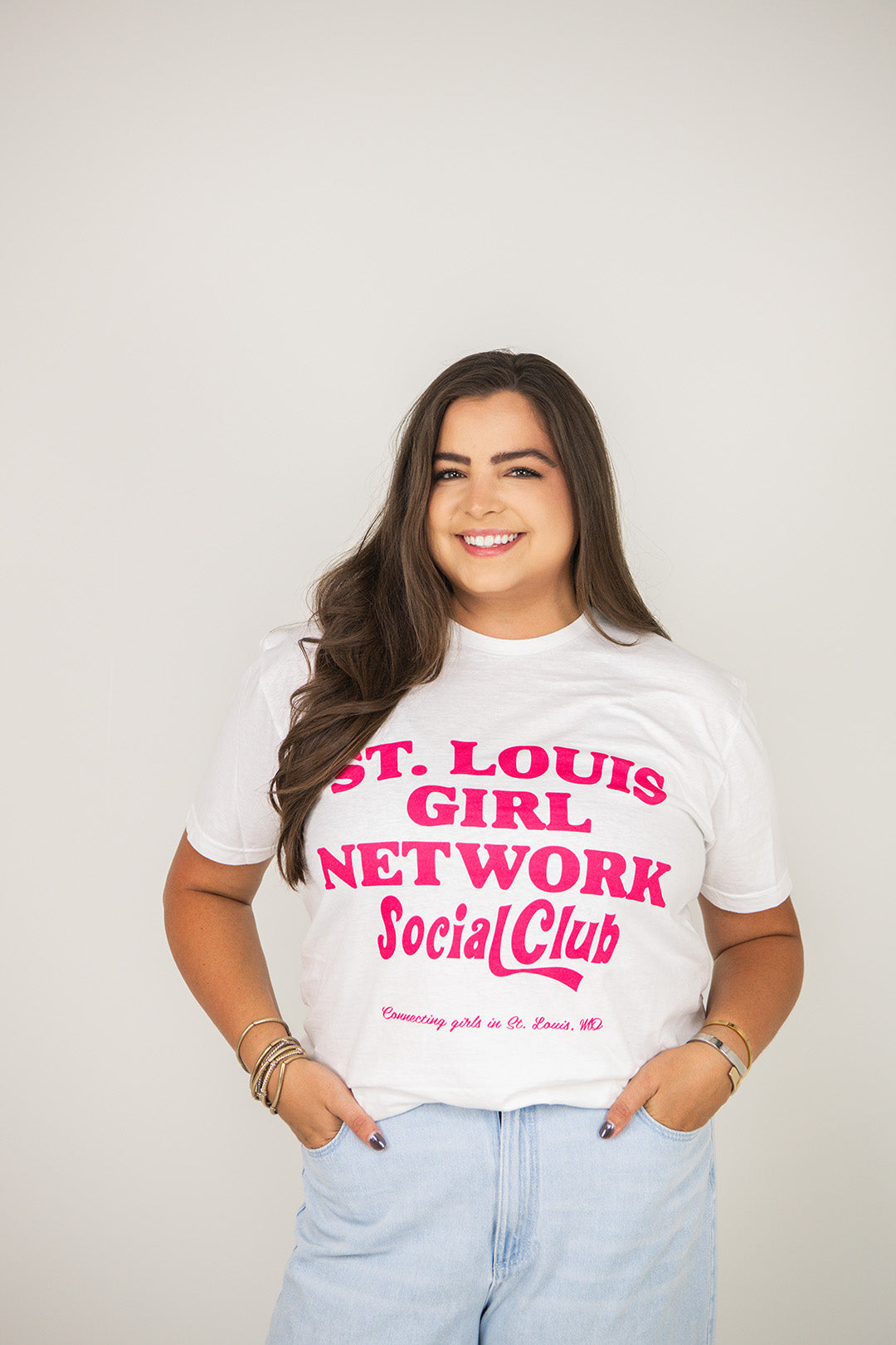 Woman wearing a white t-shirt with pink text against a plain background