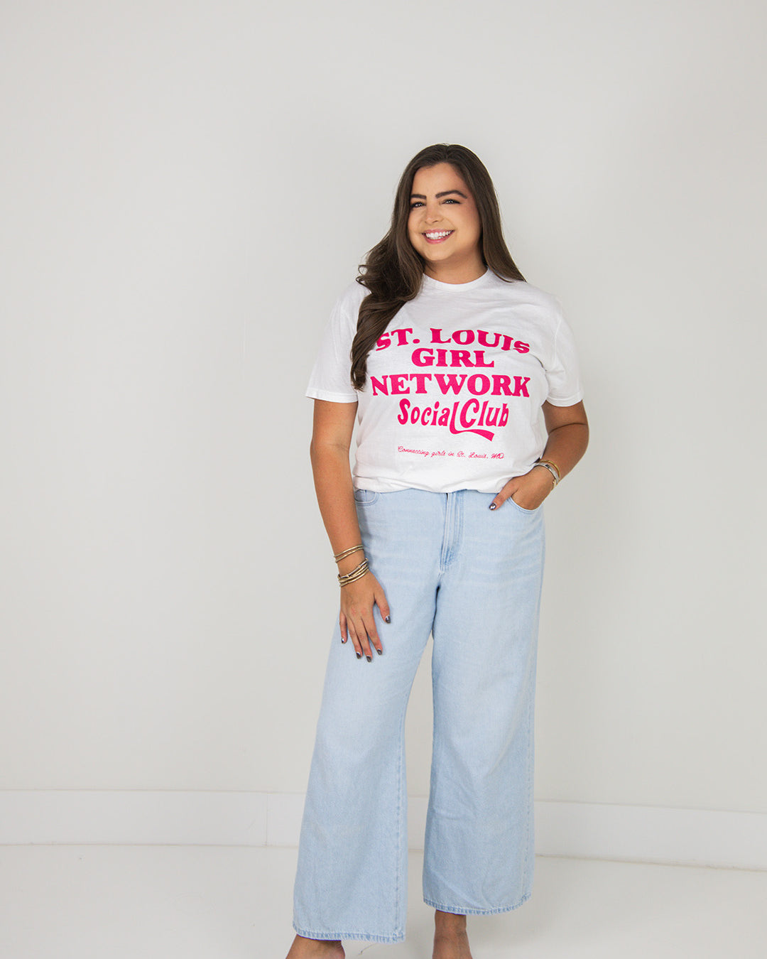 Woman wearing a white t-shirt with text and light blue jeans on a plain background