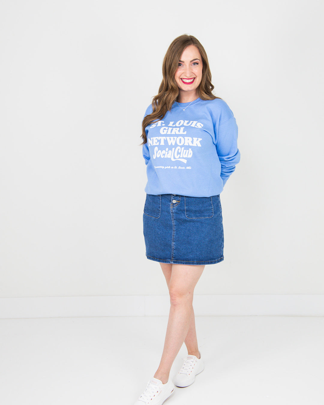 Woman wearing a blue sweatshirt and denim skirt on a white background