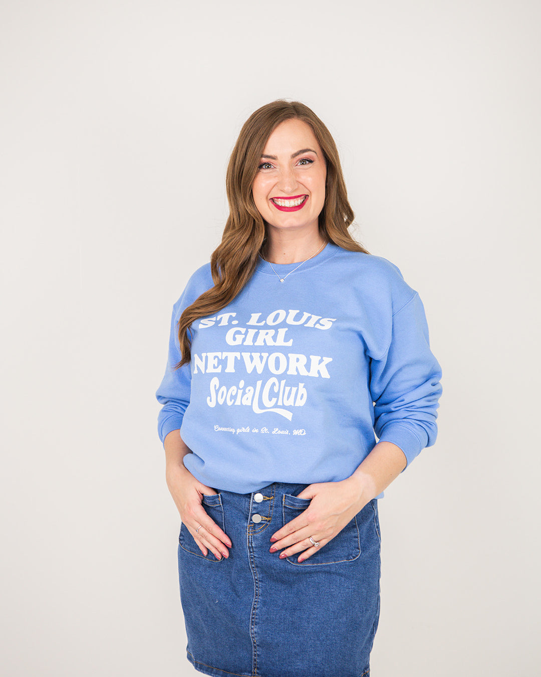 Woman wearing a blue sweatshirt with text, standing against a plain background