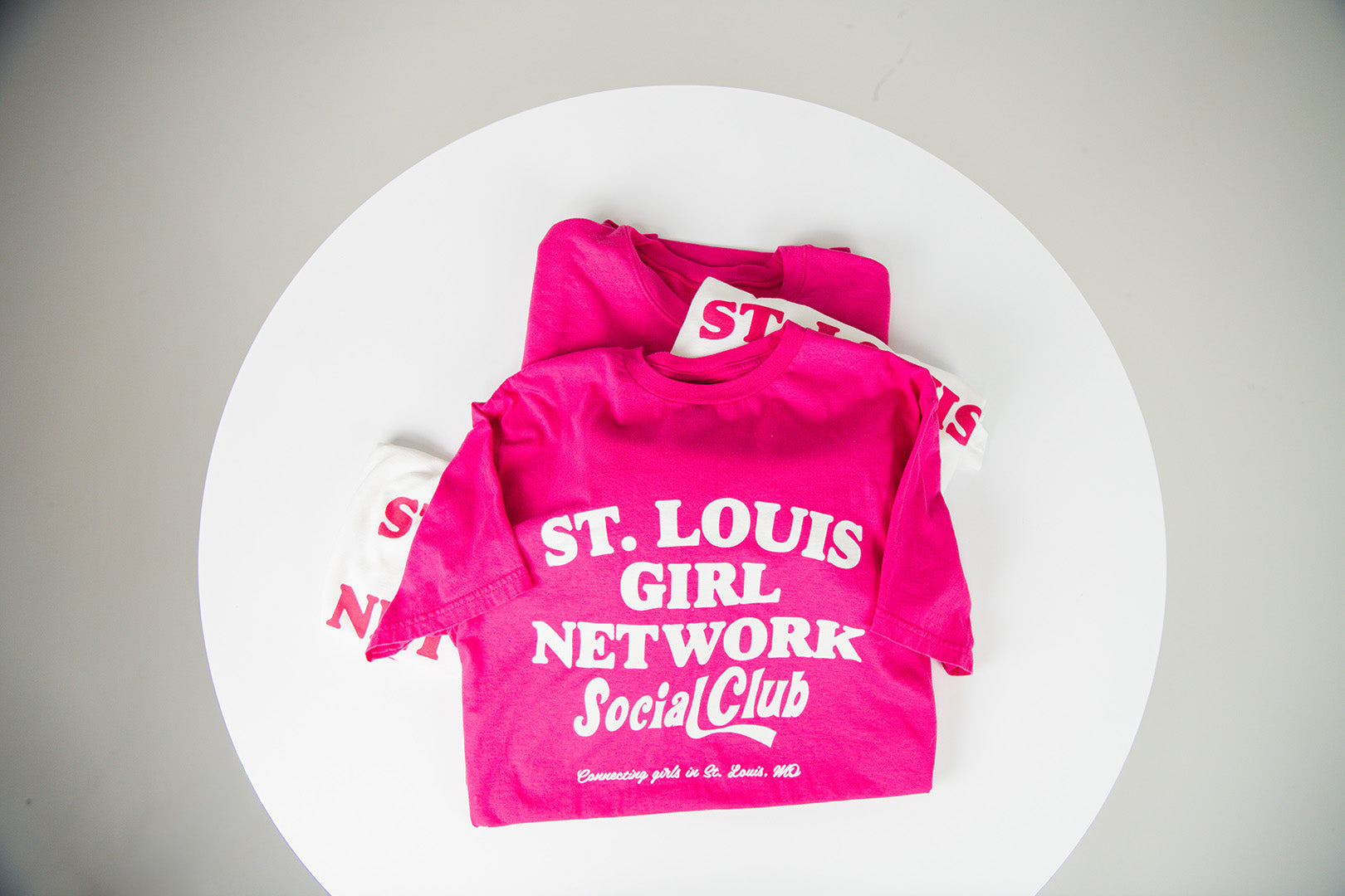 Pink t-shirt with 'St. Louis Girl Network Social Club' text on a white background