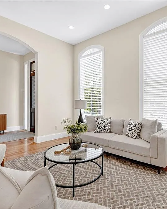 Modern living room with beige walls, gray sofa, and wooden floor.