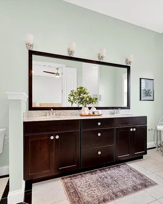 Bathroom with dark wooden vanity, large mirror, and white fixtures.