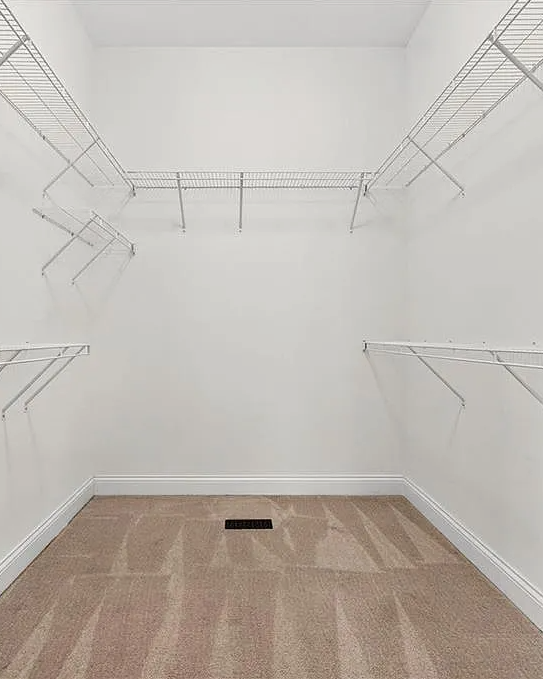 Empty closet with white walls, wooden floor, and metal rods.