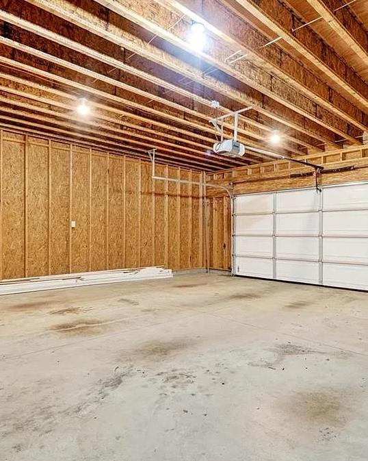 Empty garage with wooden walls and a white garage door.