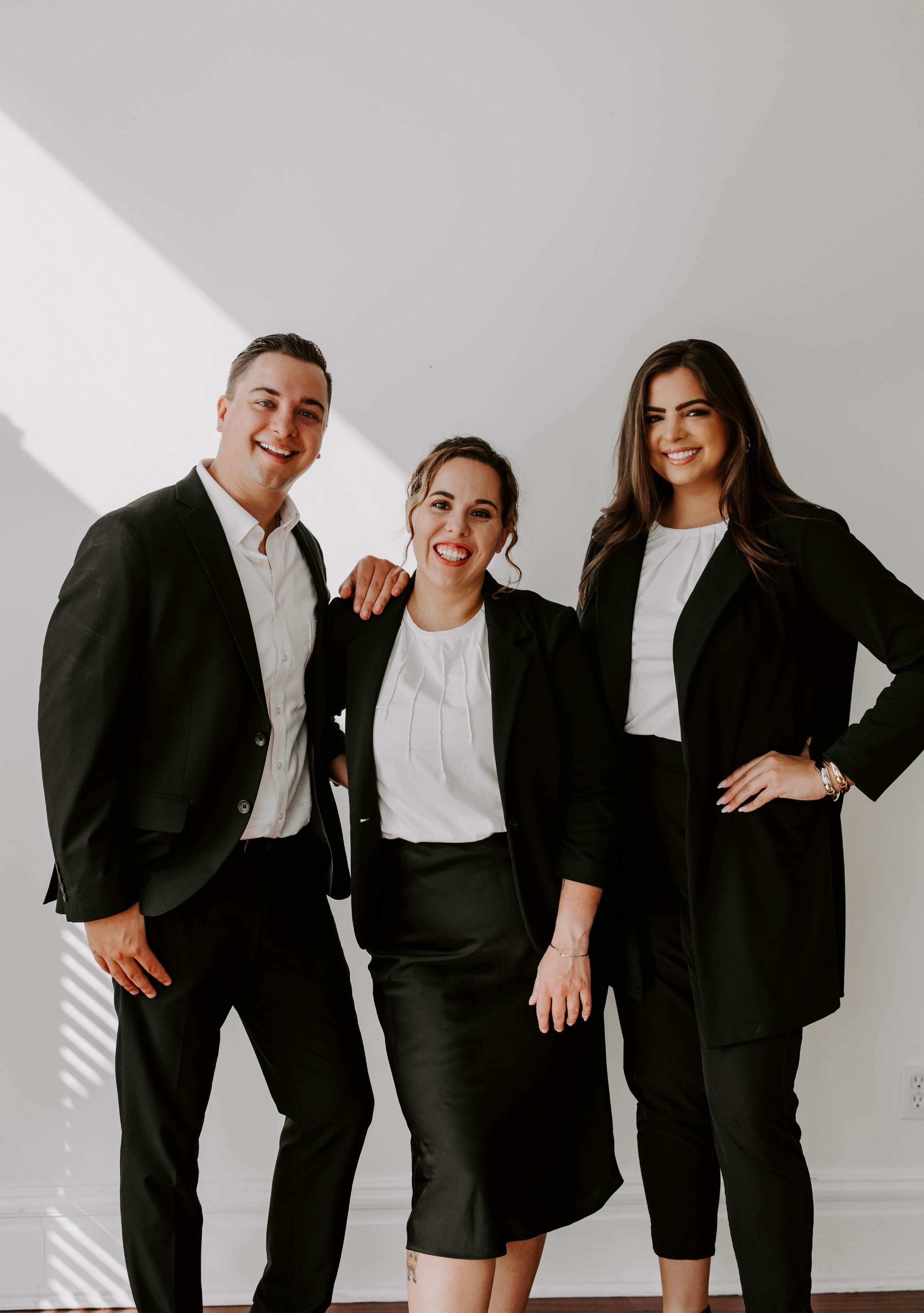 Three professionals in formal attire standing together in a well-lit room.