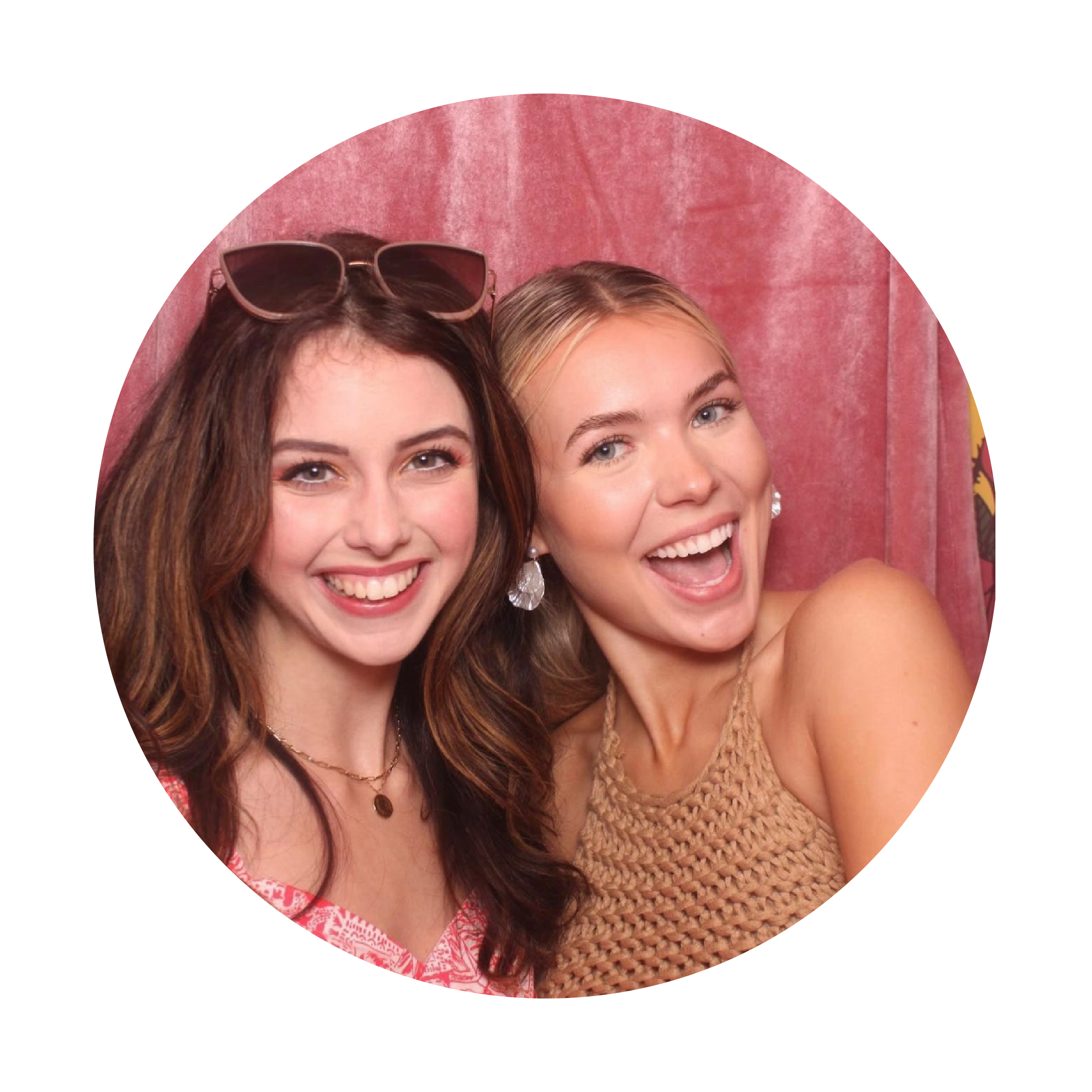 Two women smiling together with a pink background