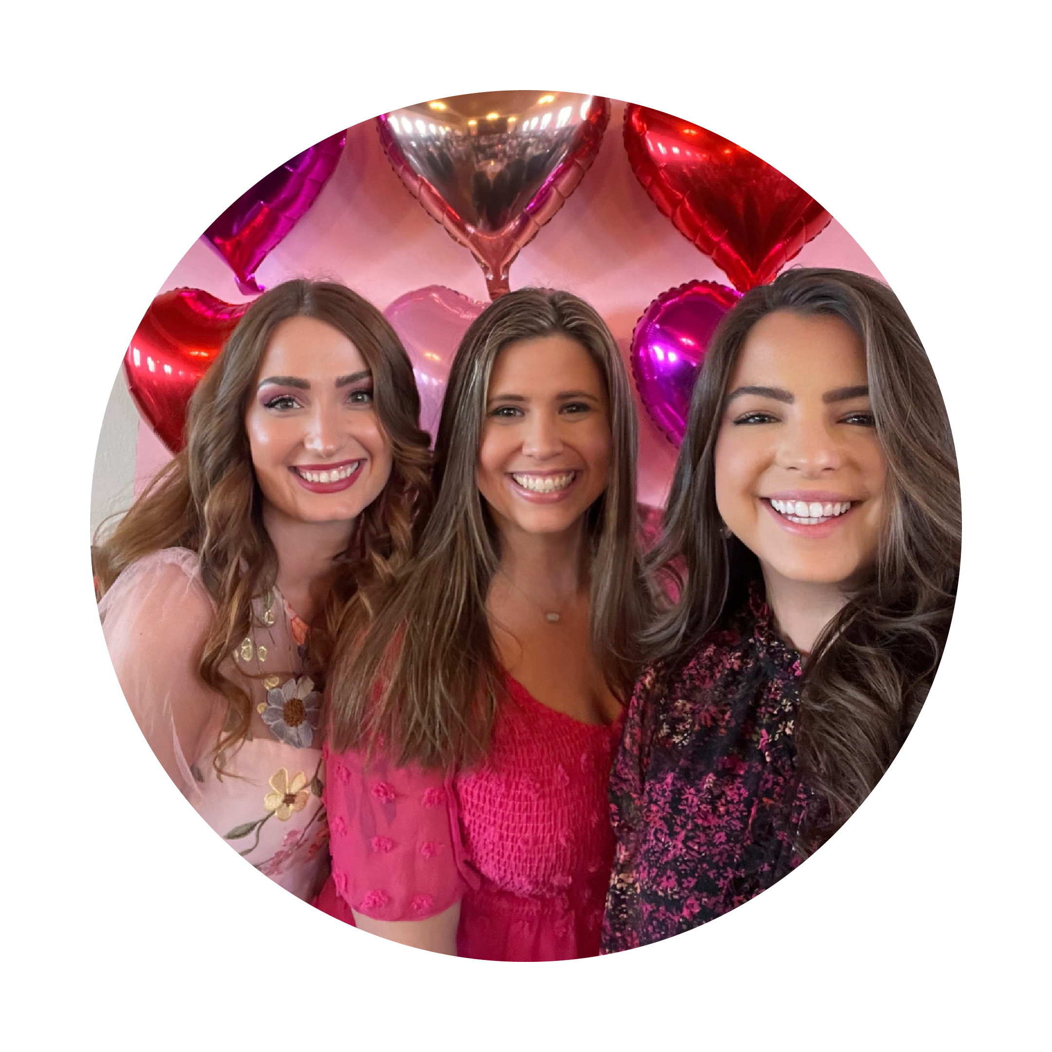 Three women standing together with heart-shaped balloons in the background