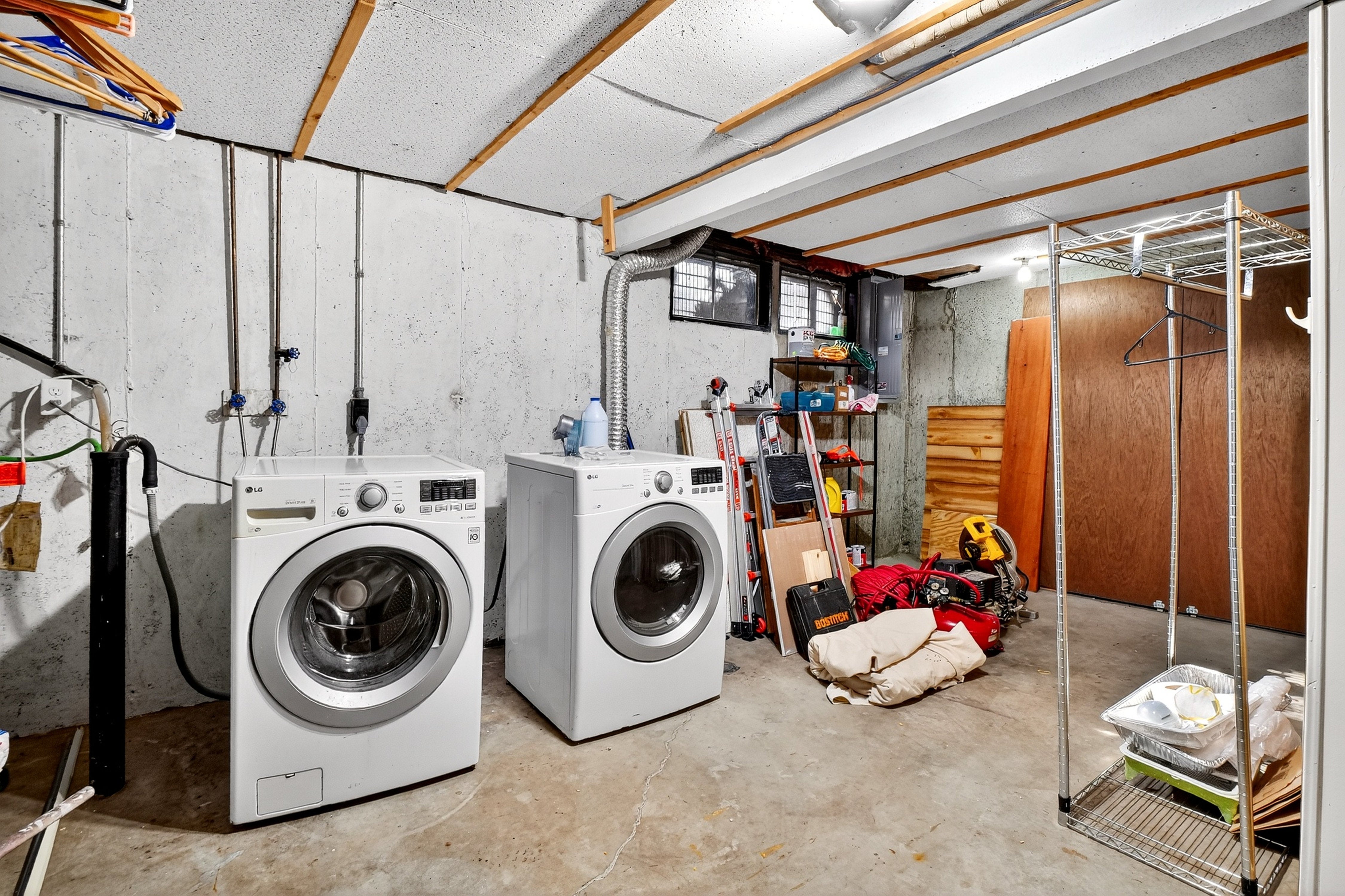 Laundry room with washing machines and various items in a basement setting