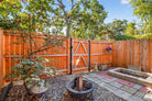 Backyard with wooden fence, fire pit, and potted plants on a sunny day.