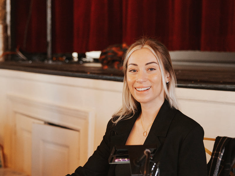 Woman with blonde hair wearing a black blazer smiling