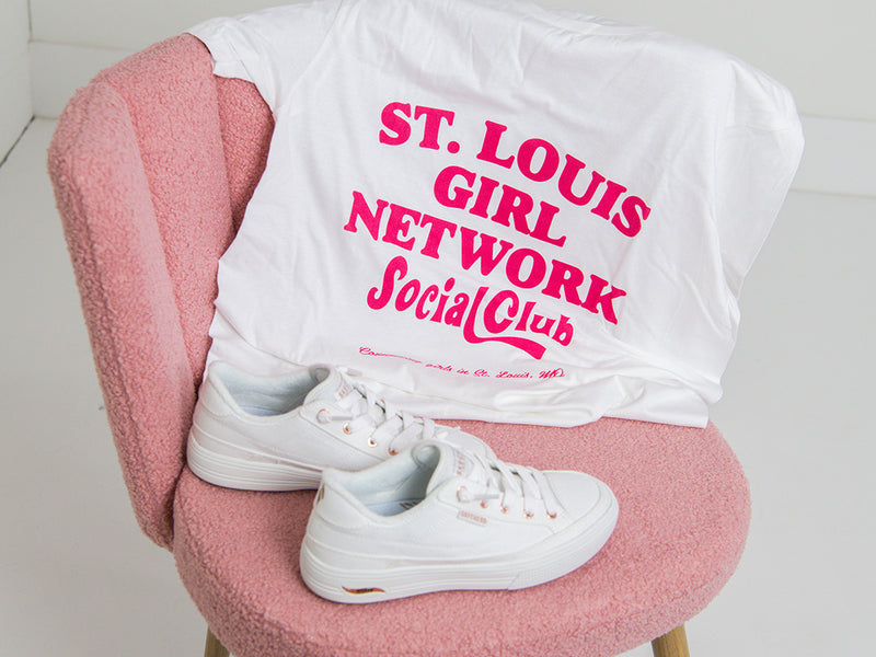 White t-shirt with pink text on a pink chair against a white background