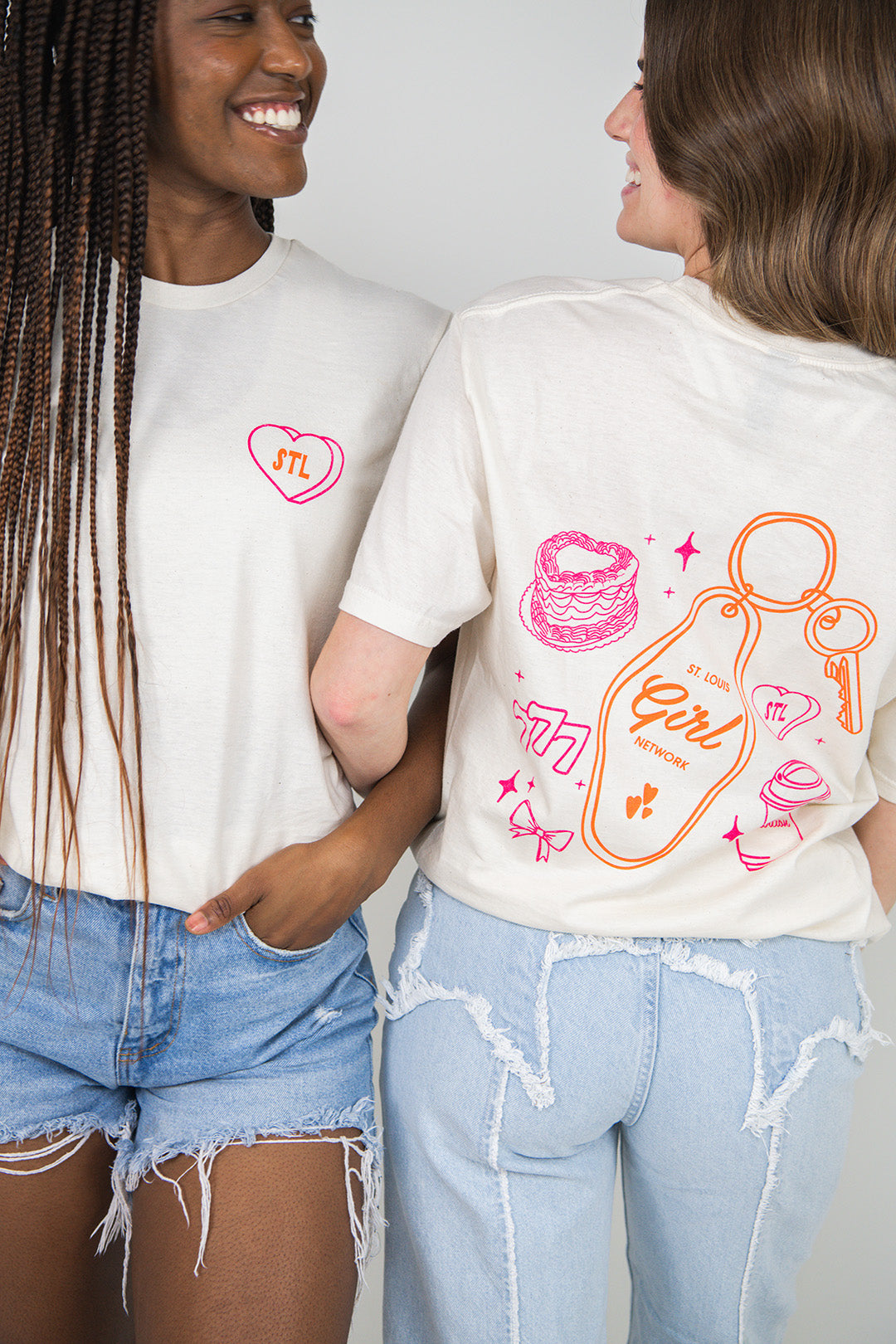 Two people wearing beige t-shirts with colorful graphics and text.