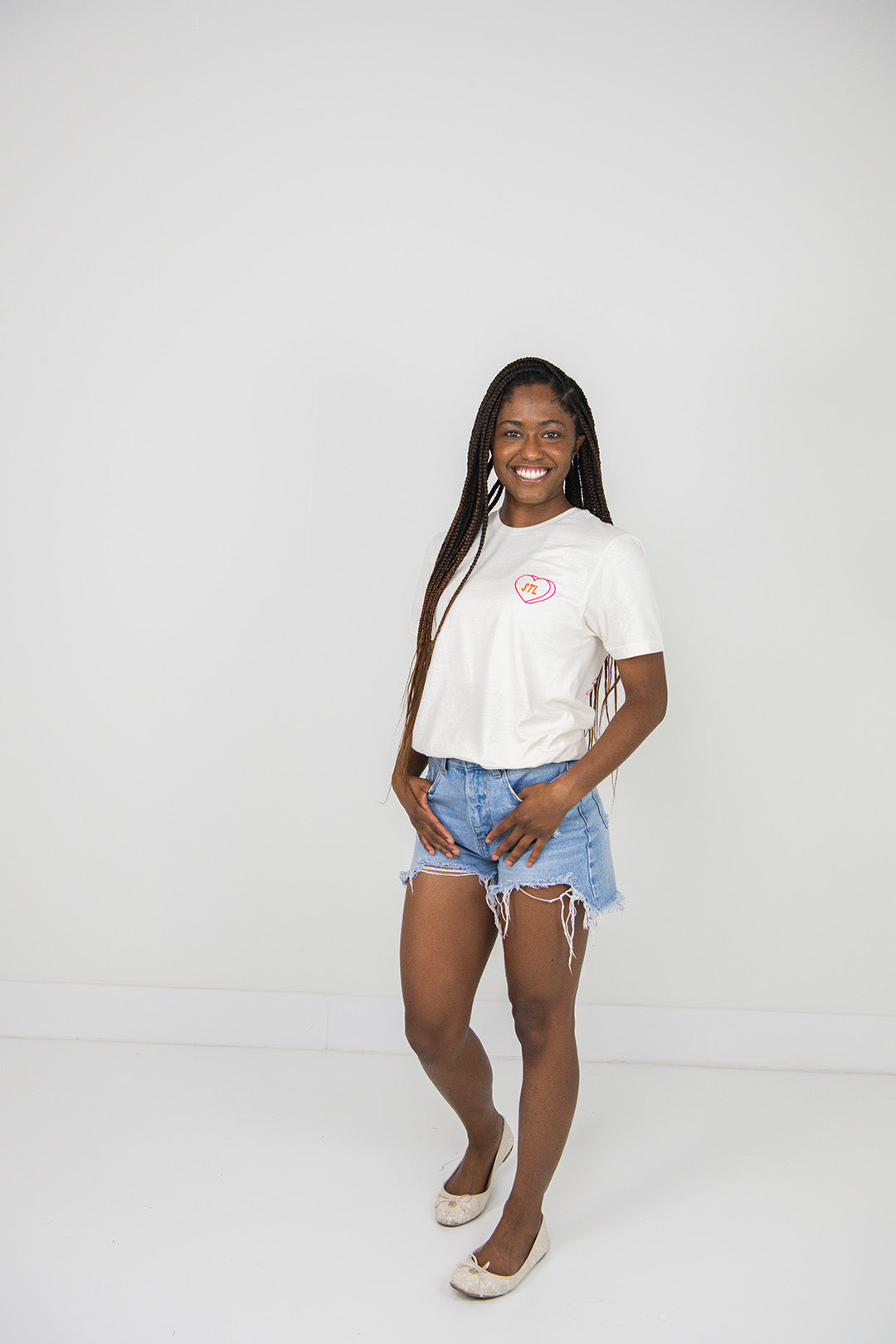 Woman wearing a beige t-shirt and denim shorts on a plain background