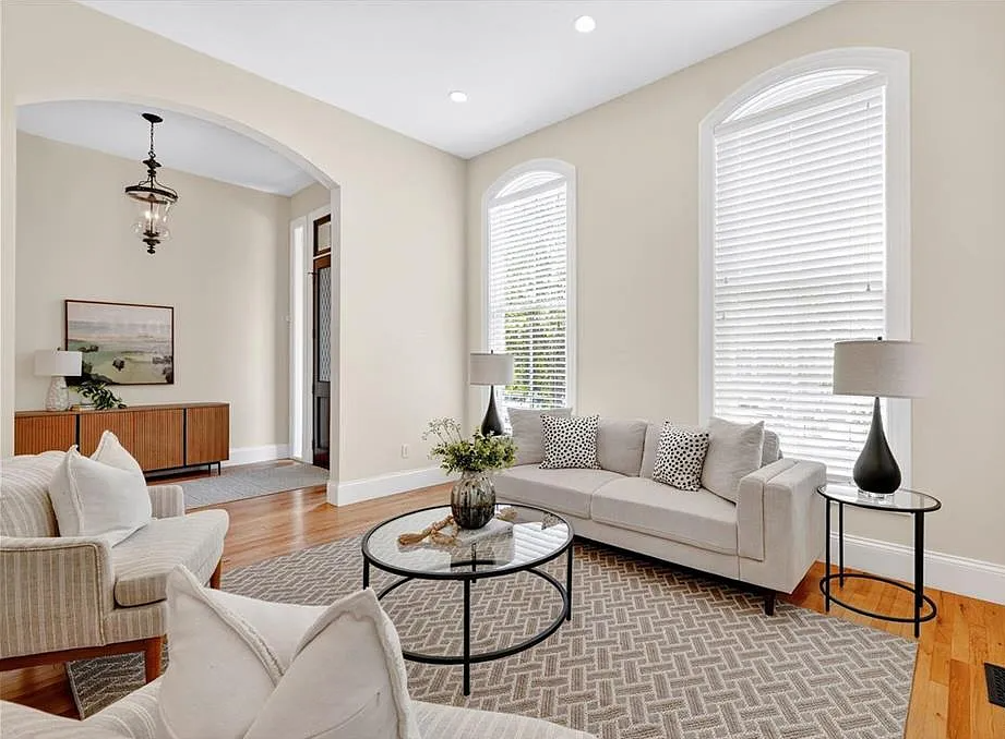 Modern living room with beige walls, gray sofa, and wooden floor.