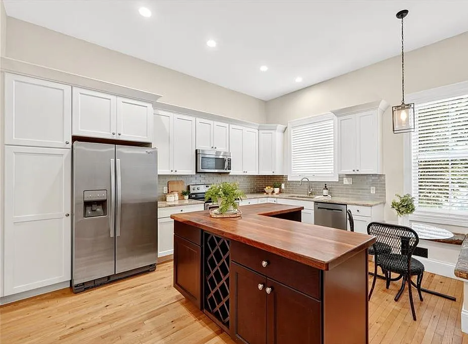 Modern kitchen with wooden island, stainless steel appliances, and white cabinets.