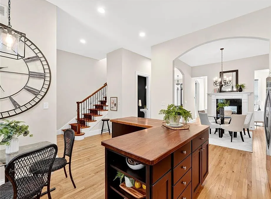 Modern home interior with wooden kitchen island, chairs, and staircase.