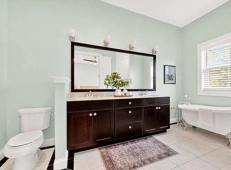 Bathroom with dark wooden vanity, large mirror, and white fixtures.