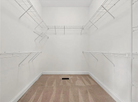 Empty closet with white walls, wooden floor, and metal rods.