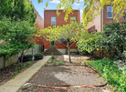 Backyard with garden bed, steps leading to a house, and trees on a sunny day.