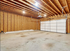 Empty garage with wooden walls and a white garage door.