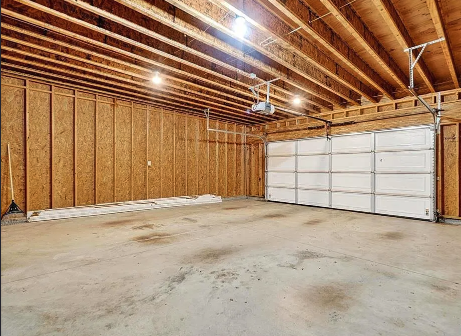 Empty garage with wooden walls and a white garage door.