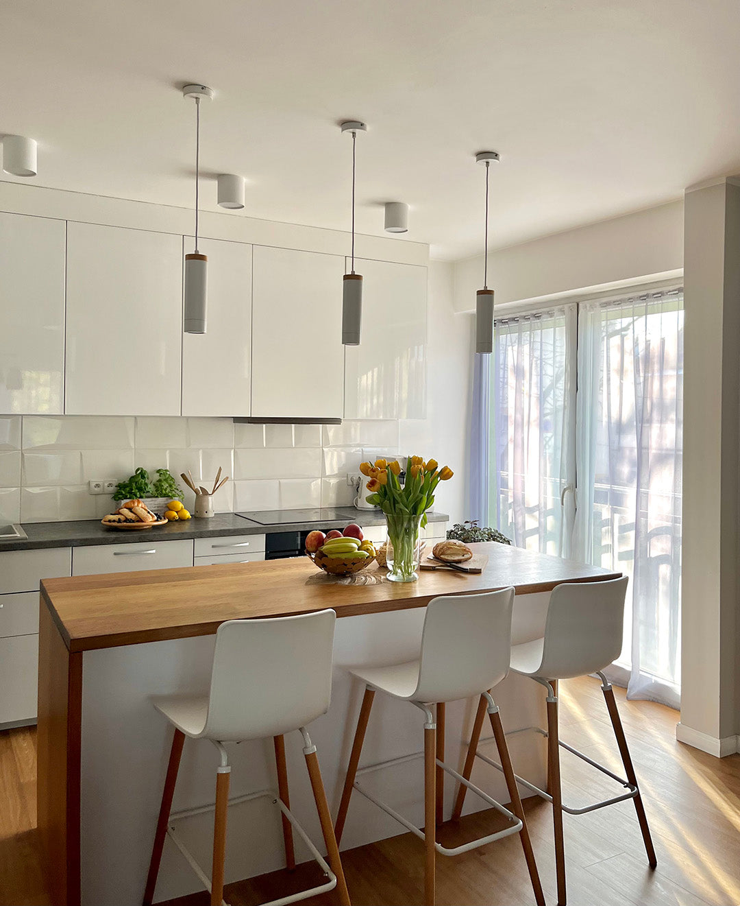 Modern kitchen with a wooden island and white bar stools.